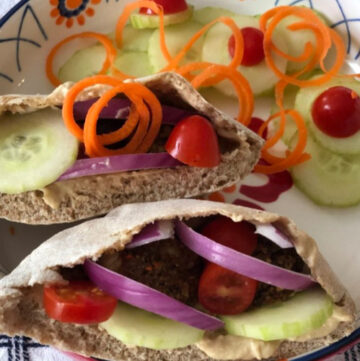 Pita pocket with meatless meatballs, tomatoes, cucumbers, red onion and a garnish of cucumbers and tomatoes