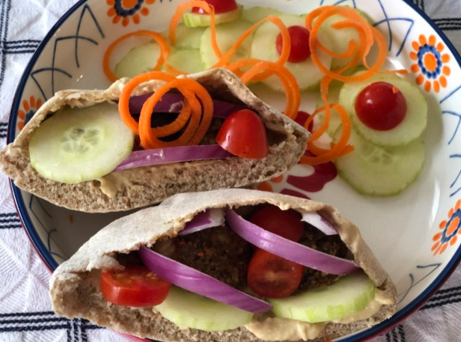 Pita pocket with meatless meatballs, tomatoes, cucumbers, red onion and a garnish of cucumbers and tomatoes