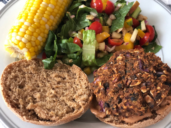 Burger plate with corn on the cob and summer salad