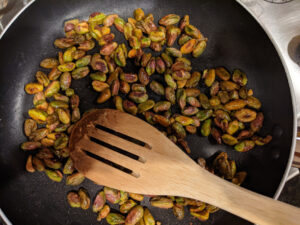 Pistachios with cayenne pepper and maple syrup in a pan